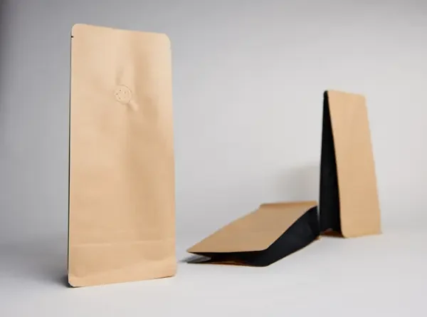 Braune und schwarze Papierverpackungen in verschiedenen Positionen auf hellem Hintergrund.