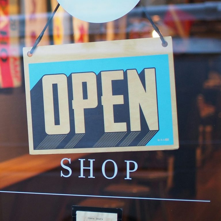 Schild mit der Aufschrift „OPEN SHOP“ an einem Fenster.